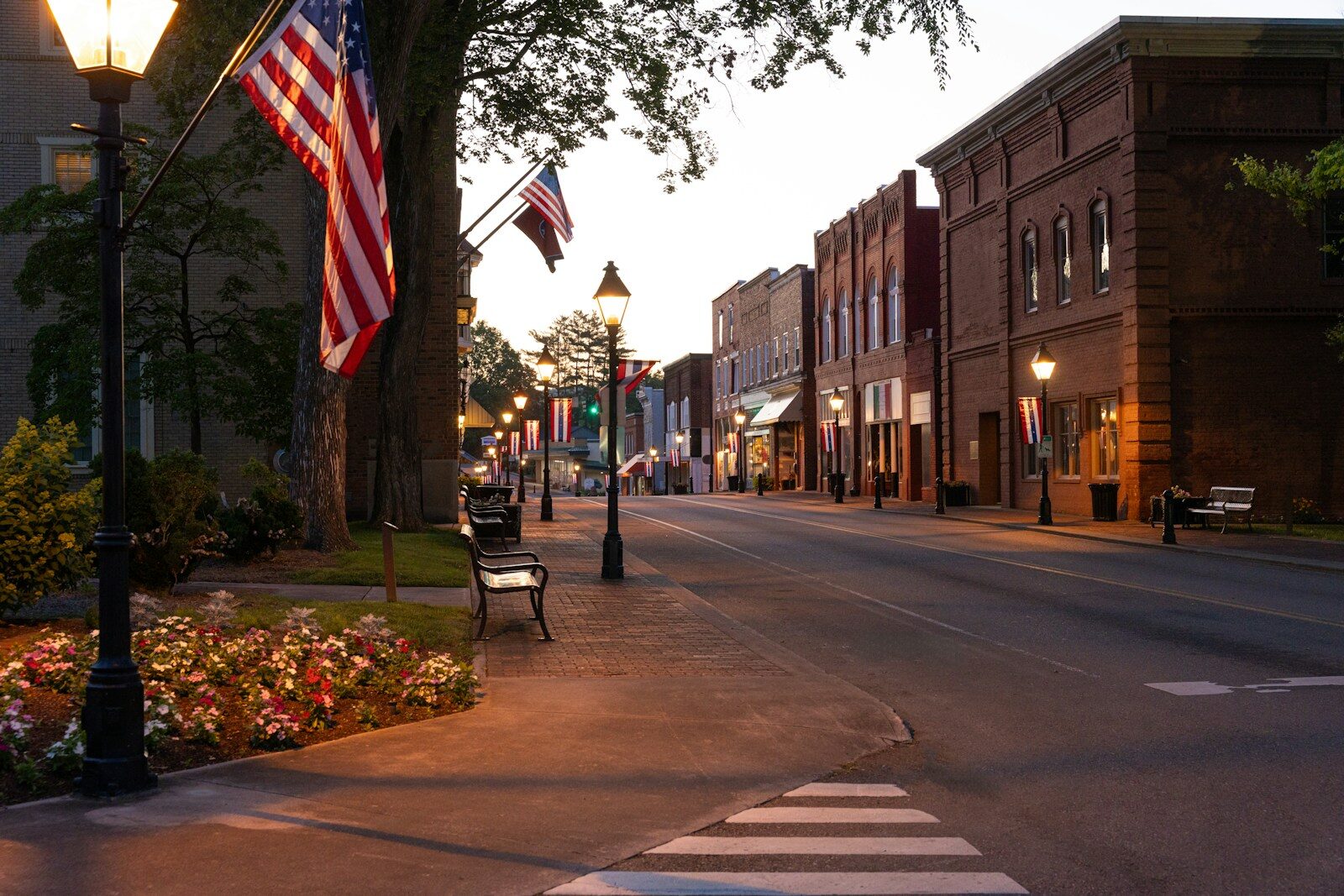Small town street at dusk with american flags.
