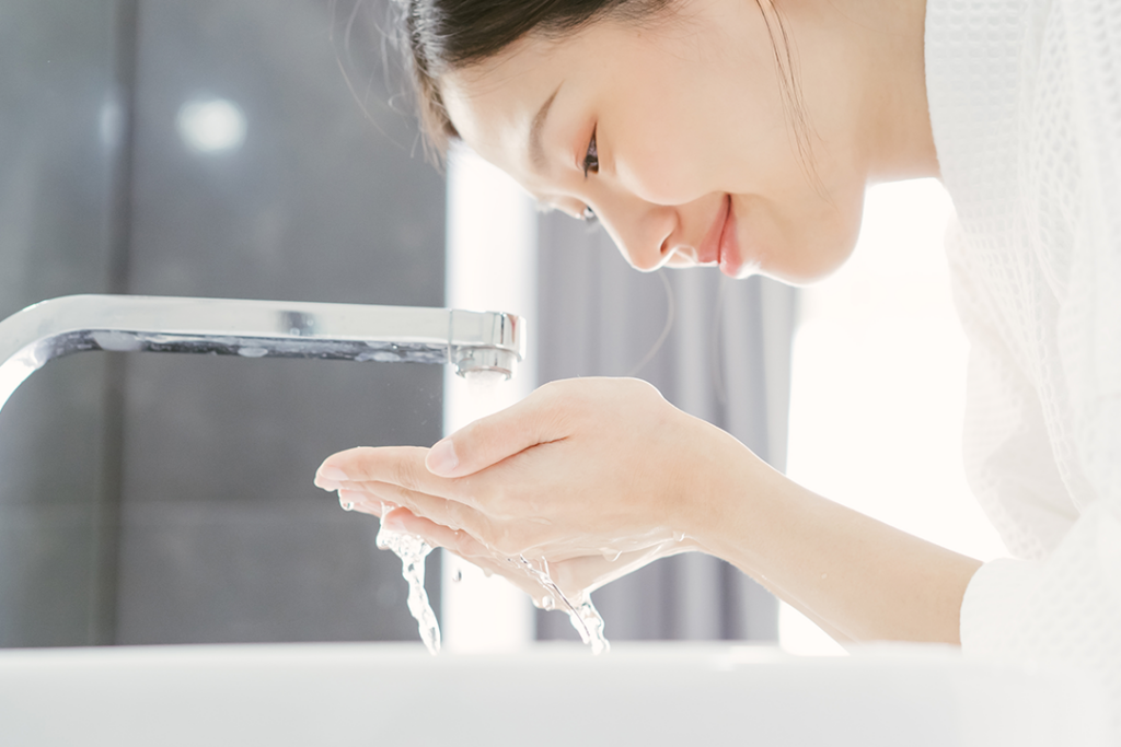 흐르는 깨끗한 물에 얼굴을 씻어내며 피부 노폐물을 제거하는 모습