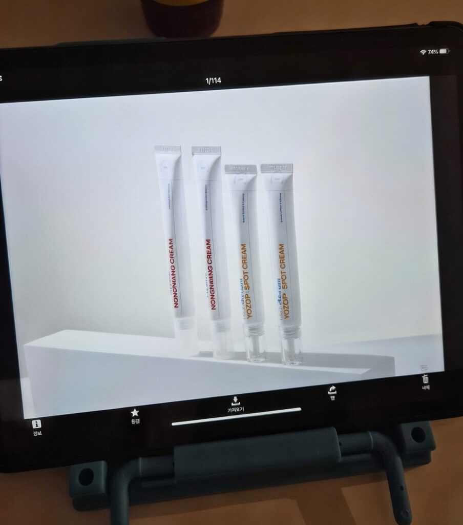 촬영 현장에서 태블릿 PC를 통해 농낭크림과 요조 스팟 크림(YOZOP SPOT CREAM)의 촬영 결과물을 모니터링하고 있는 모습입니다. 화이트 배경의 전문 화보가 기기 화면 속에 선명하게 담겨 있습니다.