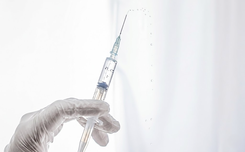 보톡스 시술 준비 — 의료용 장갑을 낀 손이 주사기를 들고 보툴리눔 톡신 약물을 확인하는 모습